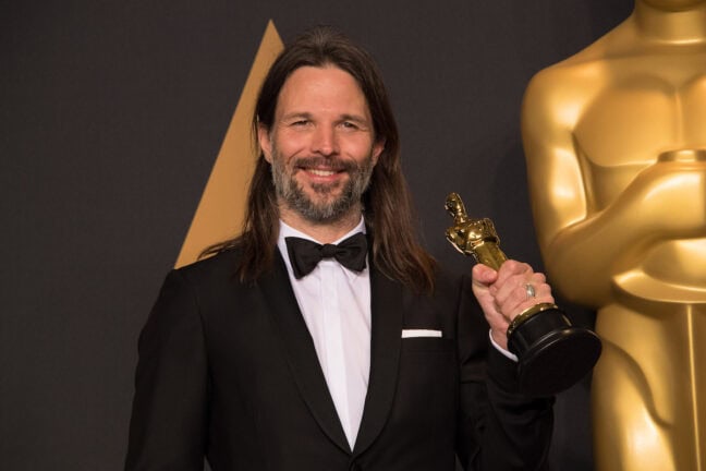 Linus Sandgren håller en Oscars-statyett i handen och ser glad ut.