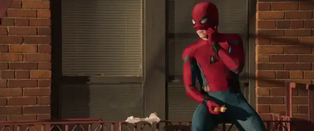 Spider-Man sitter och äter på ett balkongräcke.