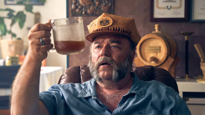 En skäggig man i övre medelåldern titttar förundrat på en genomskinlig mugg med någon slags vätska i.