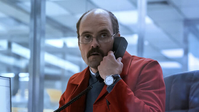 David Dencik med röd kavaj, pratar i telefon.