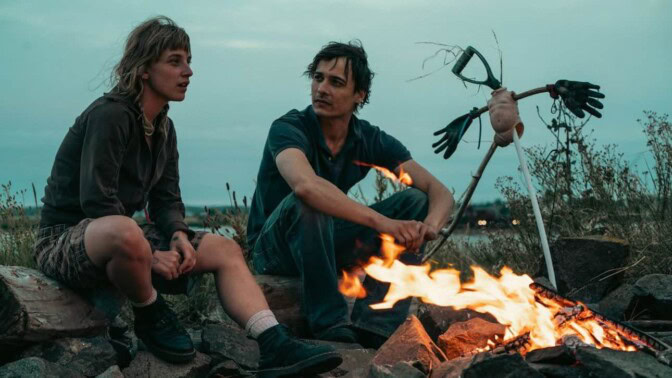 Två personer framför en lägereld.